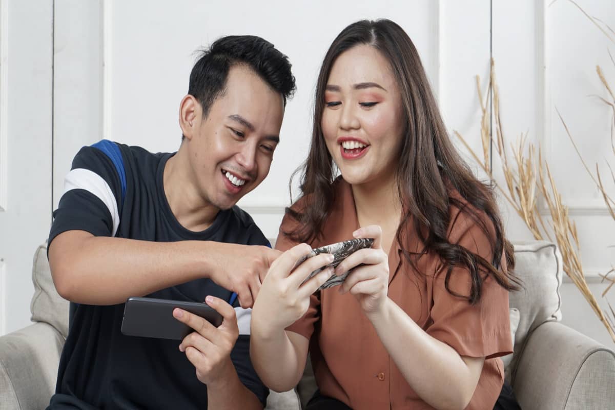 2 personnes sur canapé sourient et échangent sur leurs smartphones avec super forfaits de 20 Go chez Lebara et Lyca Mobile