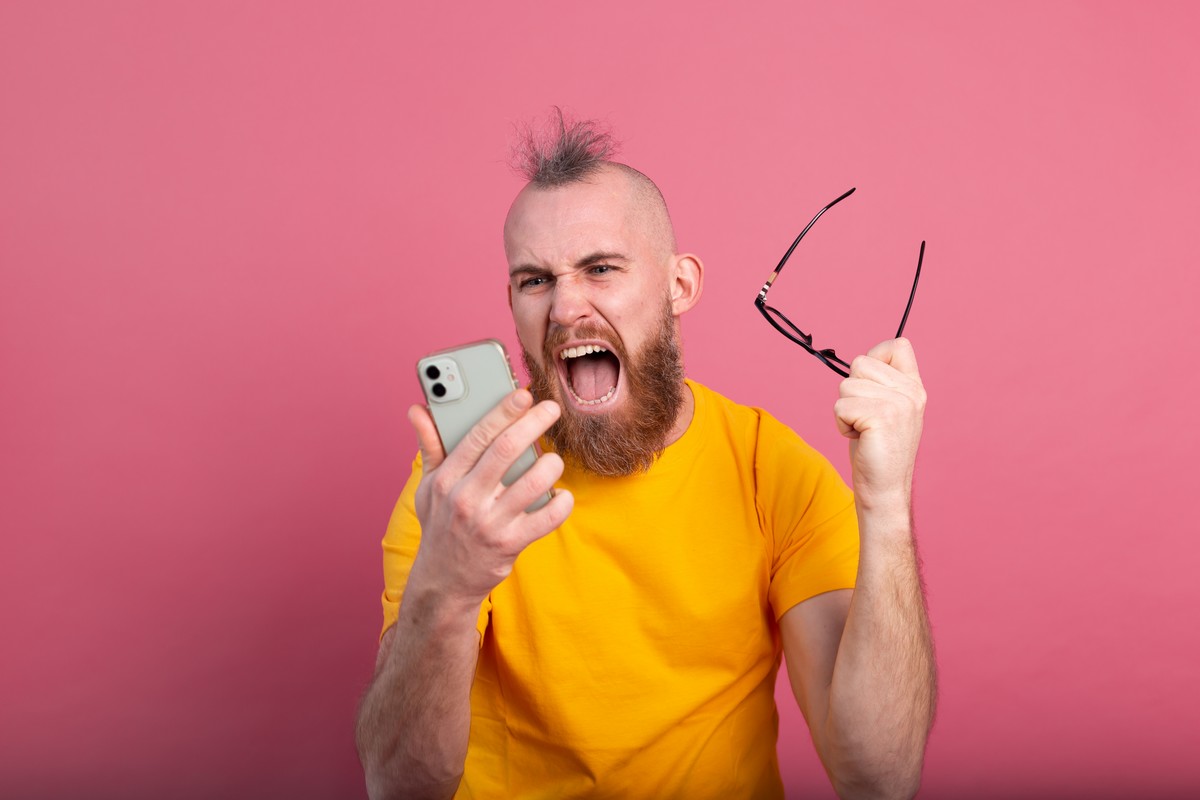 Homme Hipster sur fond rose hallucine devant son portable, un Xiaomi à moitié prix chez Amazon